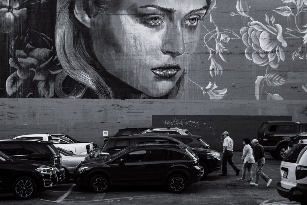 Juxtaposition of people walking before giant mural girl in Portland