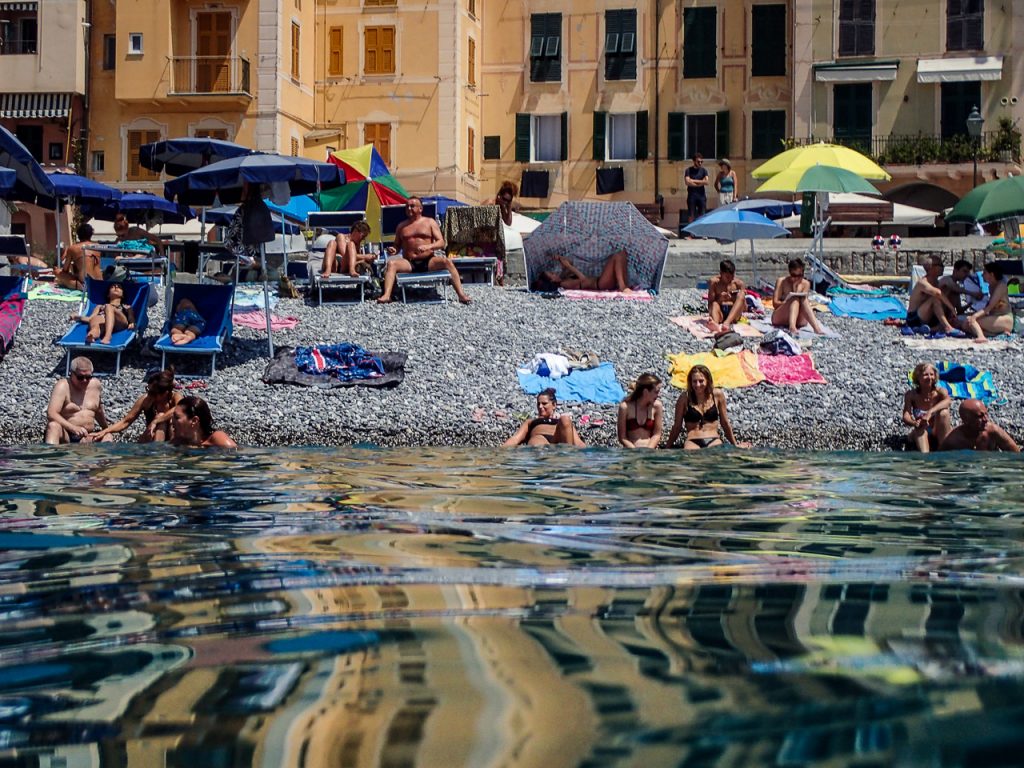 Sunbathers reflection in the water on an Italian beach