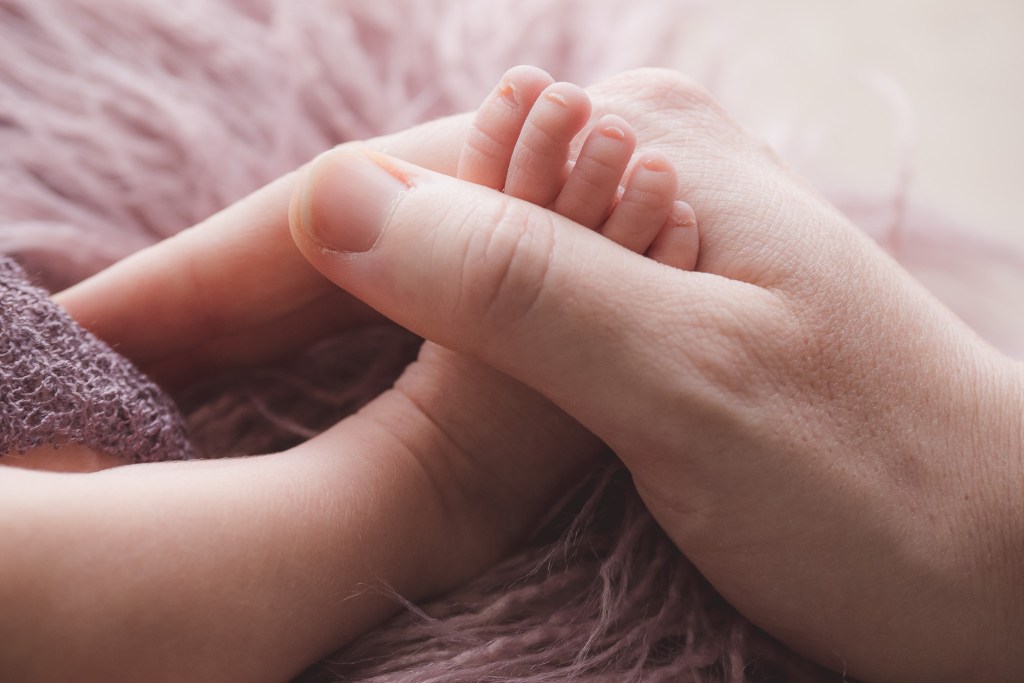 Newborn babygirl's foot in the hand of her father