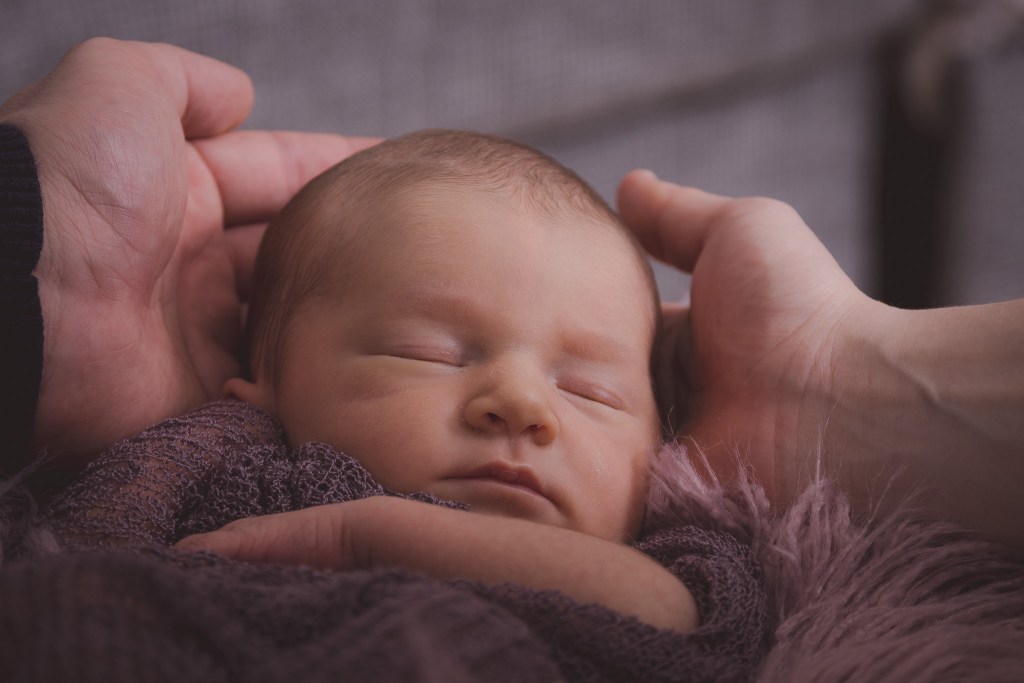 Newborn babygirl's head in the hands of her parents