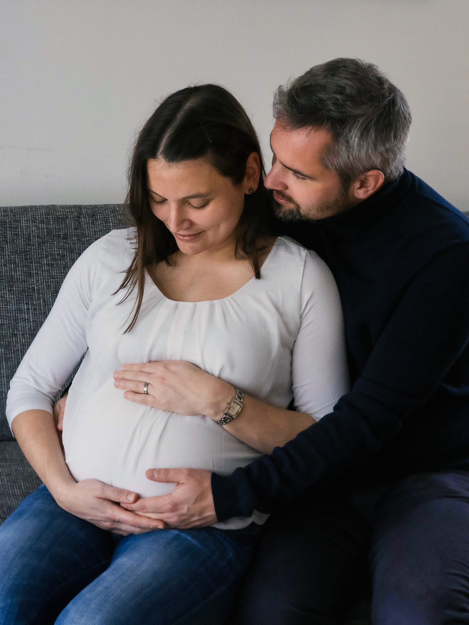 Prägnant Couple caressing the belly on their couch