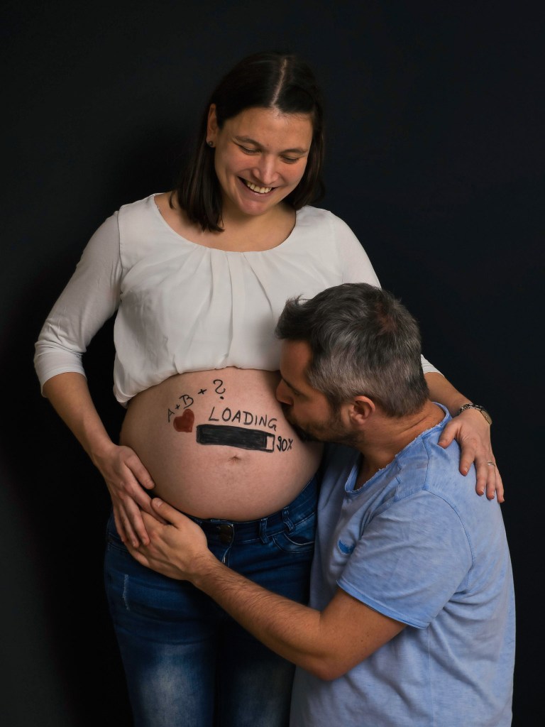 Pregnant couple having fun with a painted belly