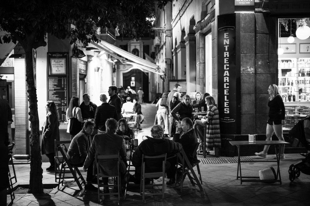 Patrons sitting in front of a bar during a night in Sevilla