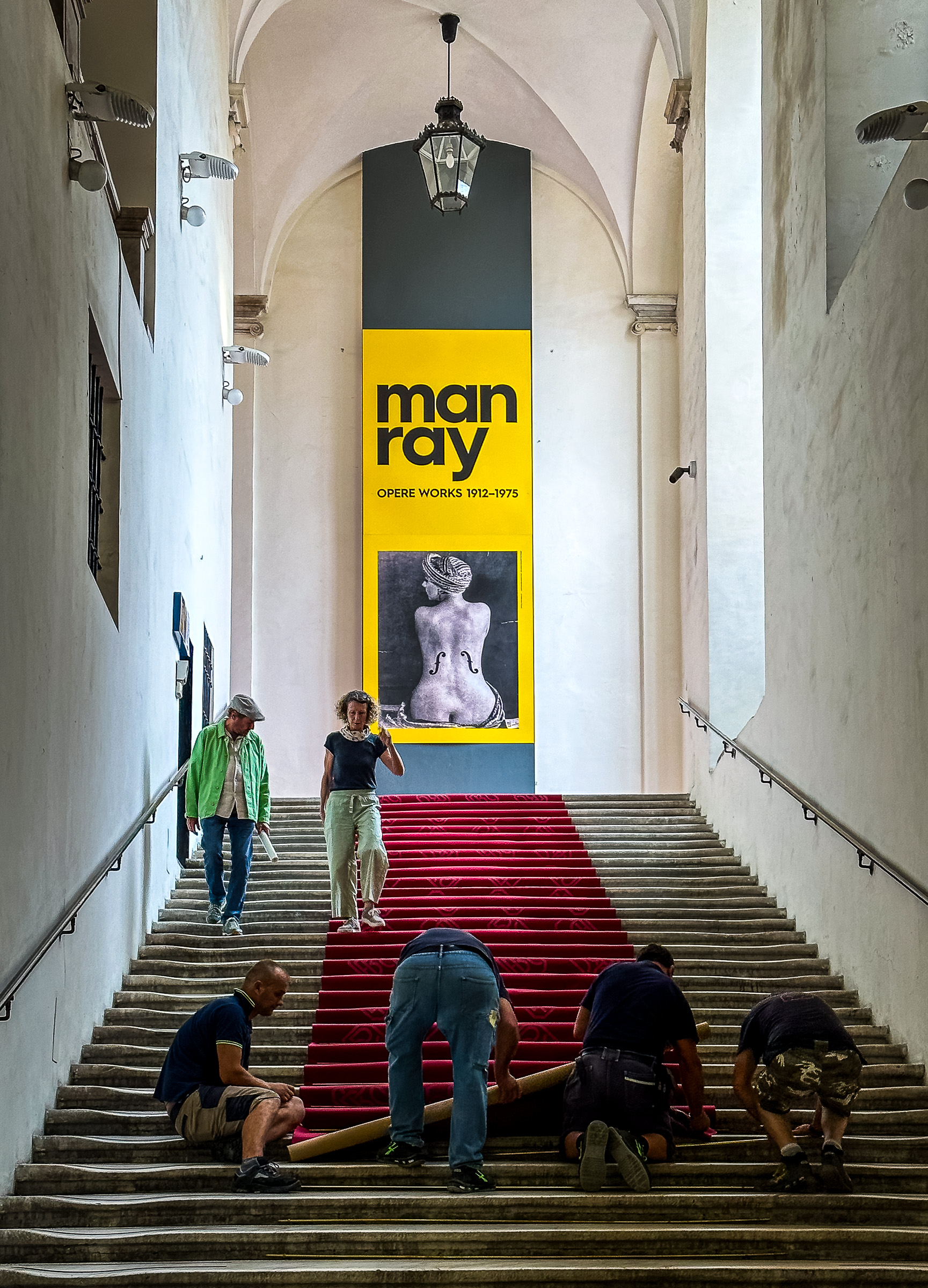 Four man rolling out a red carpet in Genoa's Palazzo Ducale