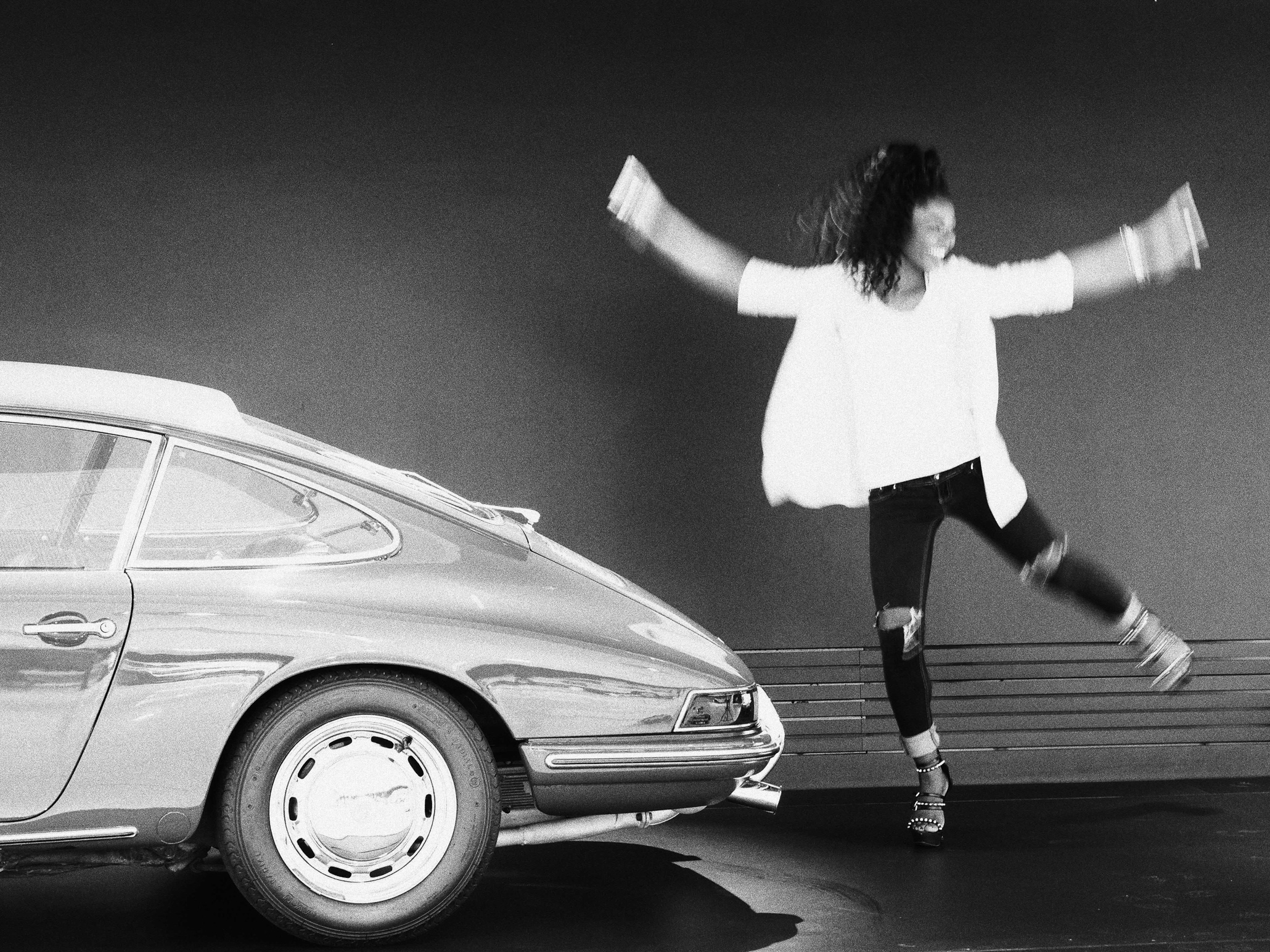 Girl dancing in front of a Porsche