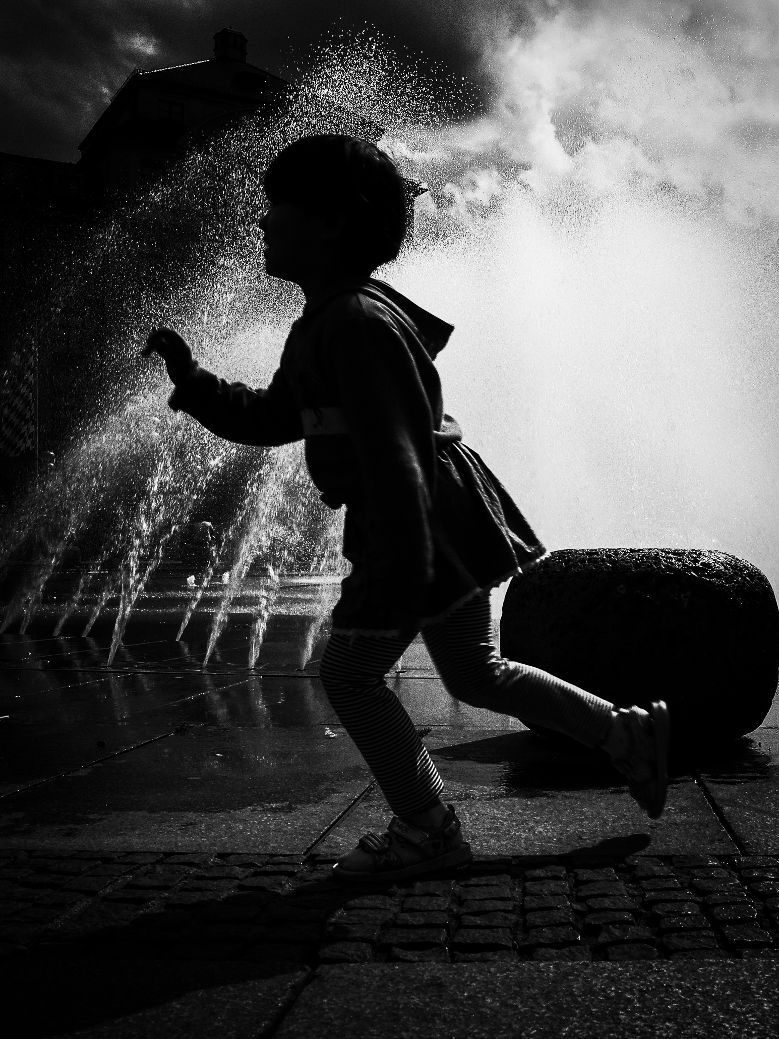 Silhouette of a child in front of a backlit fountain