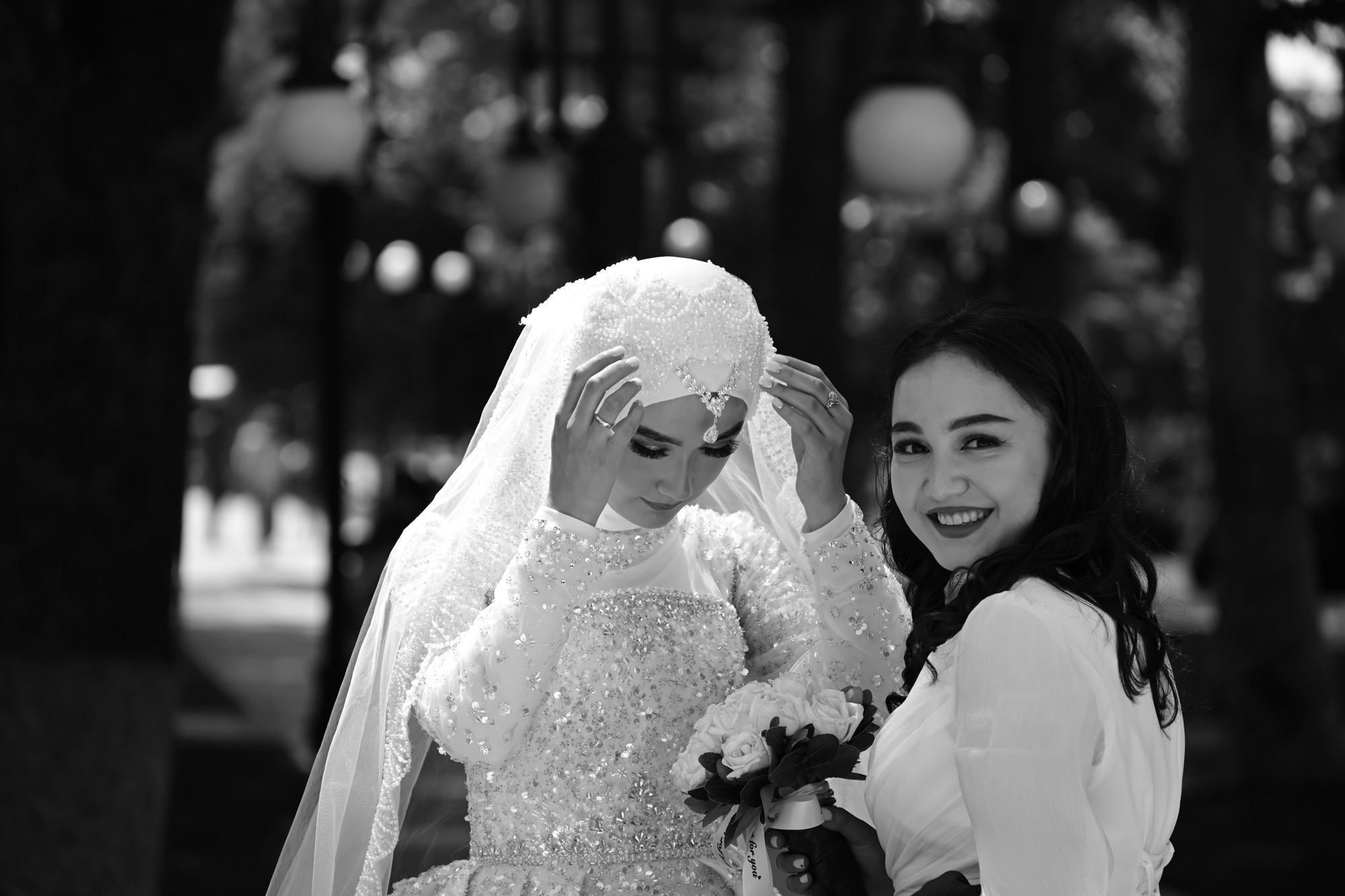A bride righting her vail on her big day while her bridesmaid smiles