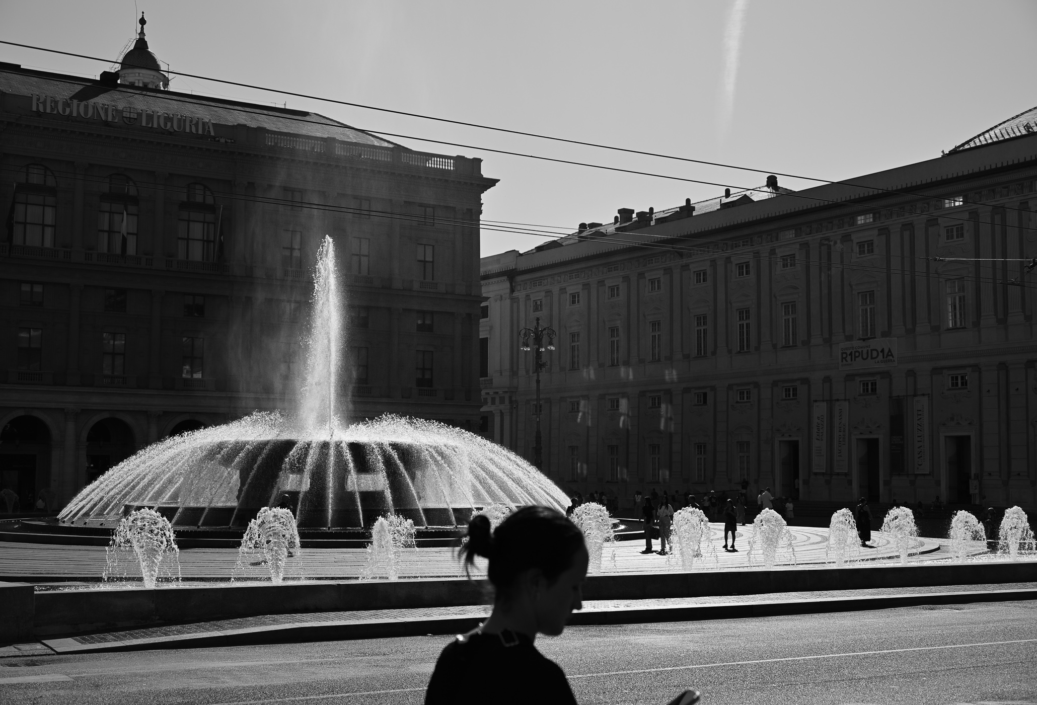 The silhouette of a lady in front of a fountain, enjoying the summer in the city