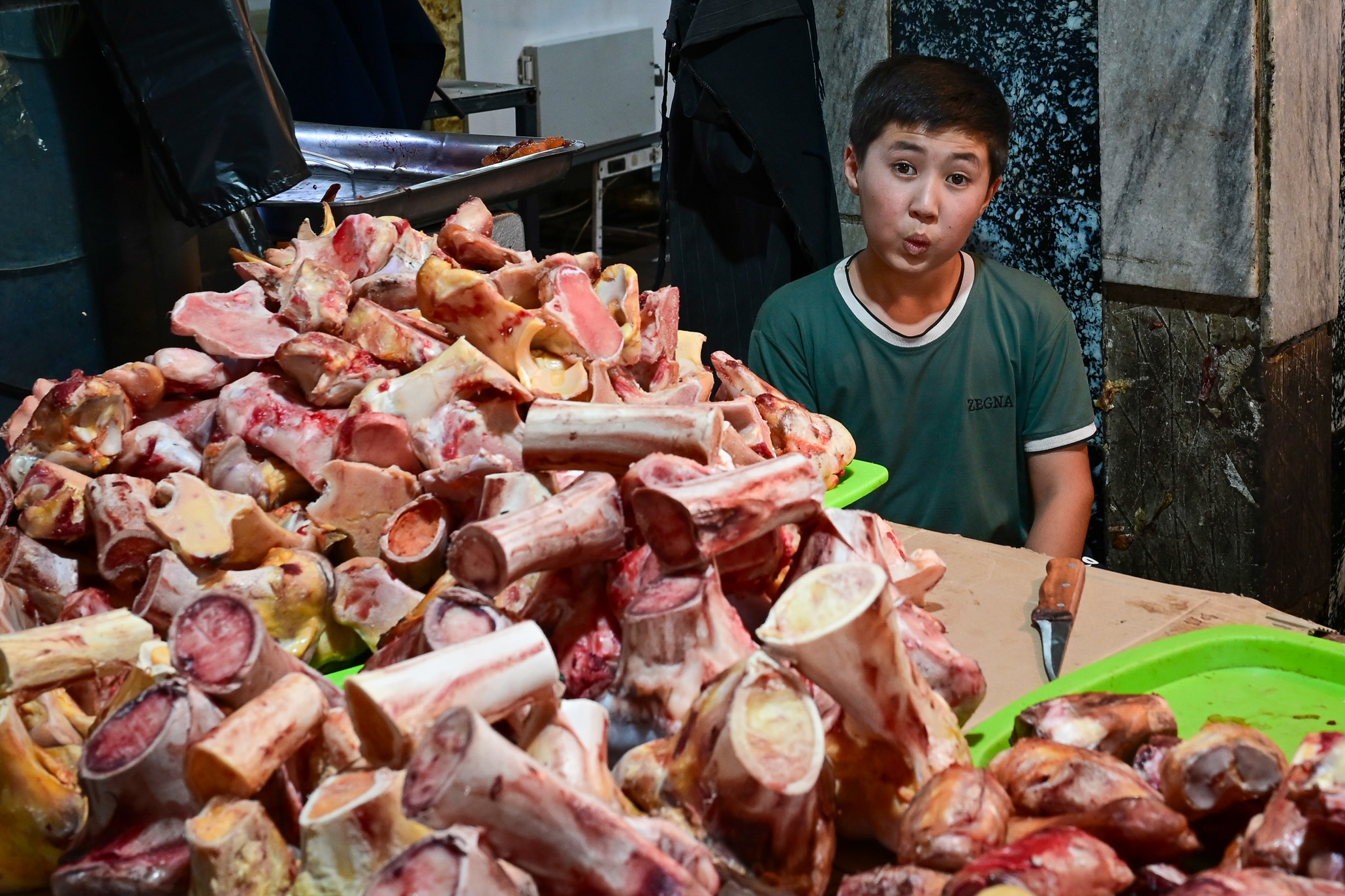 Boy selling pig-legs in an Uzbekistan market working with whistling a tune