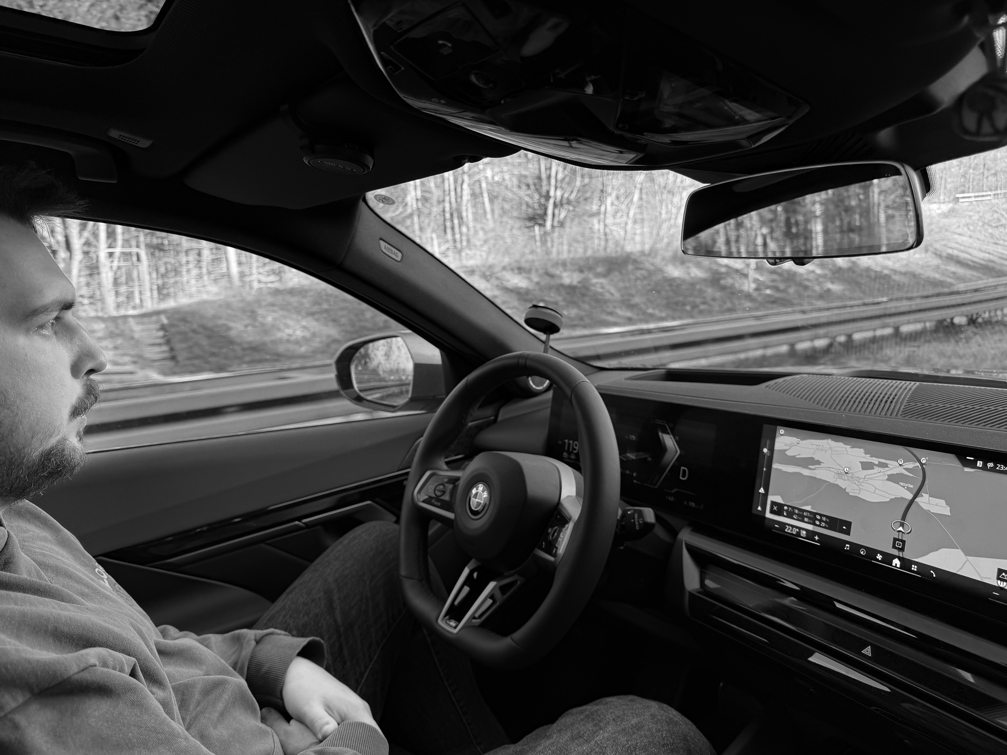 A young man sitting at the steering wheel monitoring an autonomously driving car